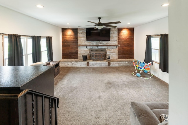 carpeted living room featuring ceiling fan and wooden walls