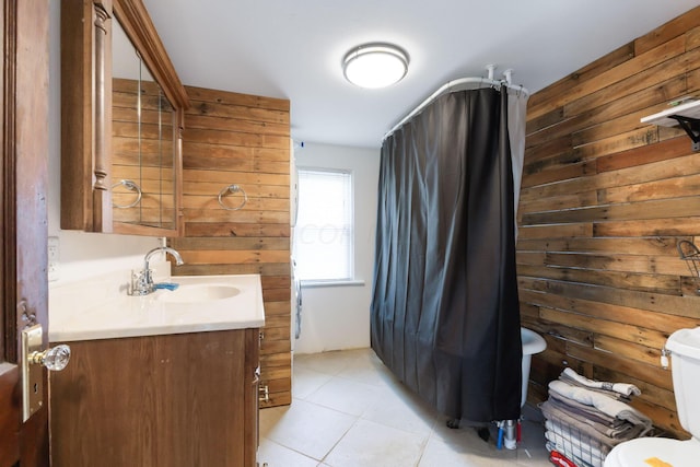 bathroom featuring tile patterned floors, vanity, toilet, and wood walls