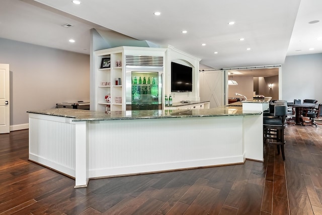 kitchen with a barn door, dark hardwood / wood-style flooring, and stainless steel built in refrigerator