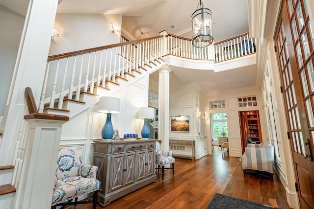 foyer featuring crown molding, a towering ceiling, dark hardwood / wood-style floors, and a notable chandelier