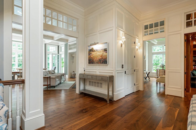 hall with decorative columns, dark hardwood / wood-style flooring, beamed ceiling, and ornamental molding