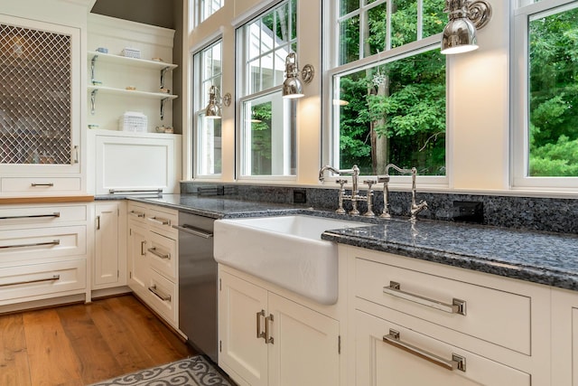 kitchen with white cabinetry, sink, dark stone counters, and dark hardwood / wood-style floors