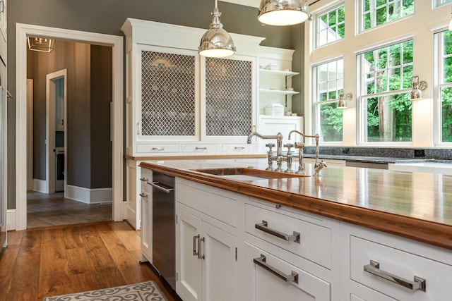 kitchen featuring wooden counters, white cabinets, sink, hanging light fixtures, and dark hardwood / wood-style floors