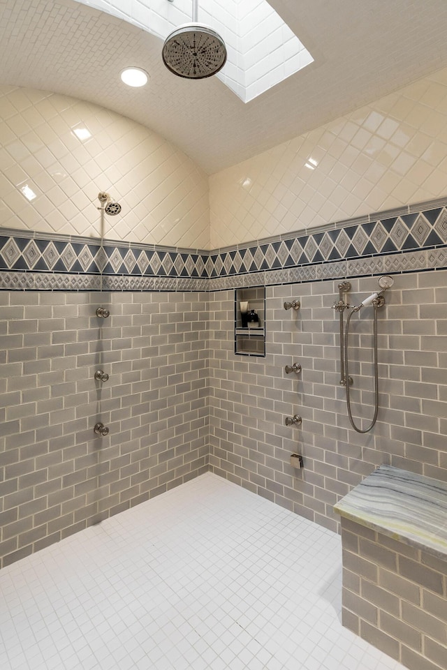 bathroom with tile patterned flooring, a tile shower, and vaulted ceiling with skylight