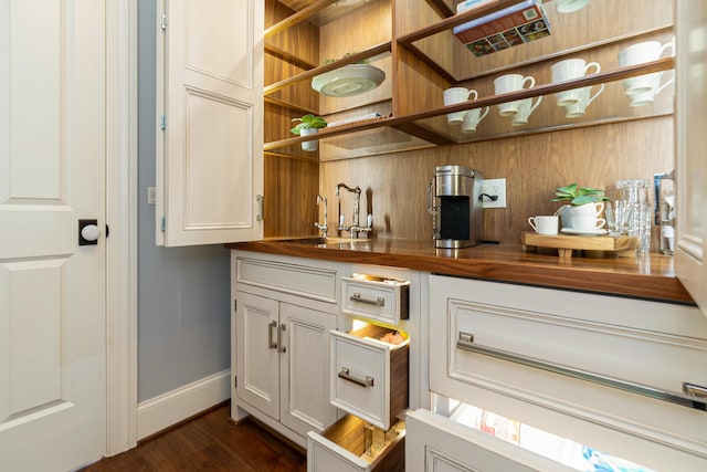 bar featuring dark wood-type flooring, white cabinets, wooden counters, and sink