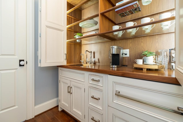 bar featuring white cabinets, wood counters, sink, and dark wood-type flooring