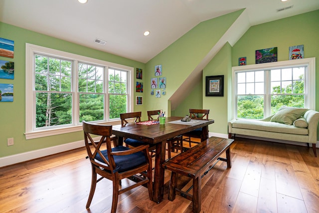 dining area featuring a healthy amount of sunlight, lofted ceiling, and light hardwood / wood-style flooring