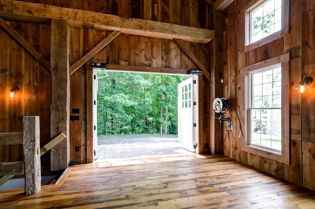 interior space featuring wood walls, light wood-type flooring, and beam ceiling