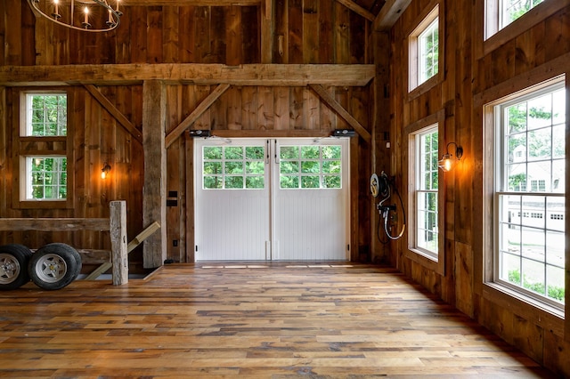 unfurnished living room with wood walls, wood-type flooring, and a high ceiling