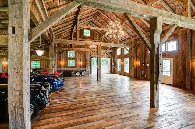 misc room with beam ceiling, an inviting chandelier, high vaulted ceiling, wood walls, and hardwood / wood-style floors