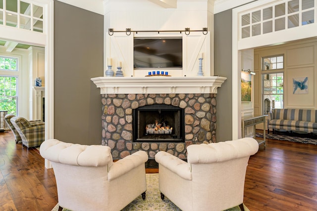 living room with ornamental molding, a stone fireplace, dark wood-type flooring, and a high ceiling