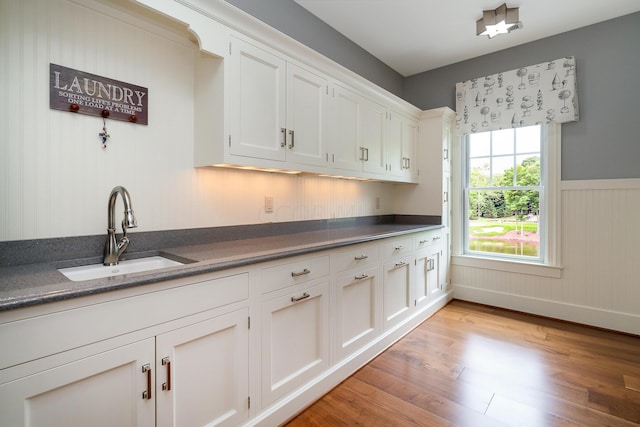 kitchen with white cabinets, sink, and light hardwood / wood-style flooring