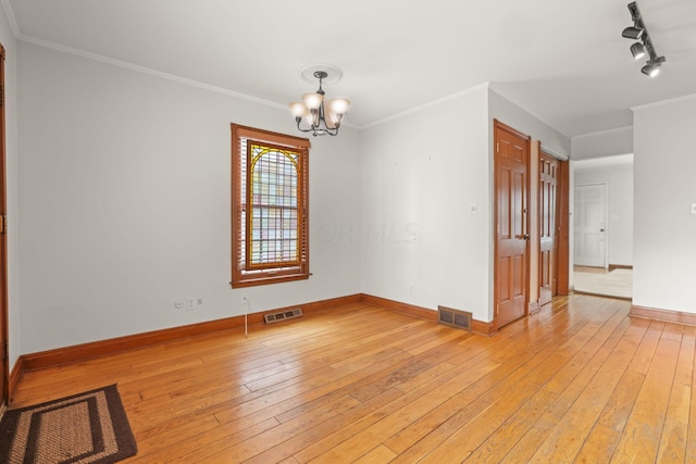 spare room featuring crown molding, light hardwood / wood-style floors, track lighting, and a notable chandelier