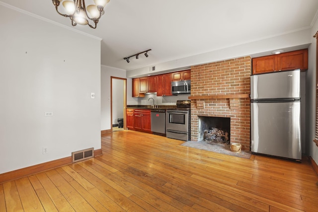 kitchen featuring ornamental molding, rail lighting, light wood-type flooring, and appliances with stainless steel finishes