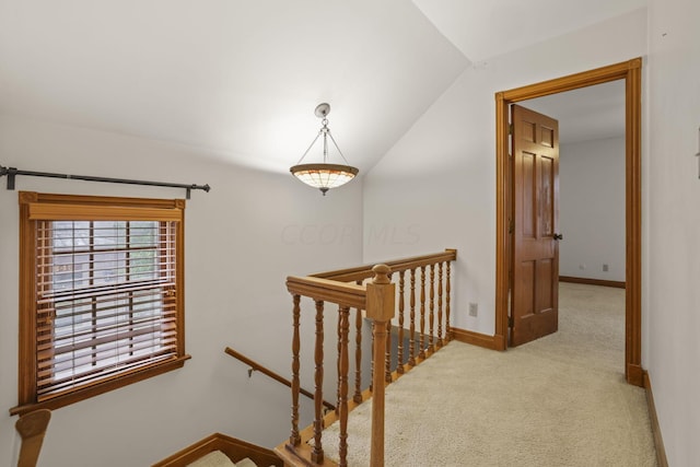 hallway with light colored carpet and vaulted ceiling