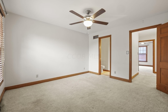 unfurnished bedroom with ceiling fan, light colored carpet, and connected bathroom