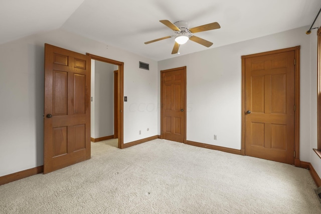 unfurnished bedroom with light colored carpet, vaulted ceiling, and ceiling fan