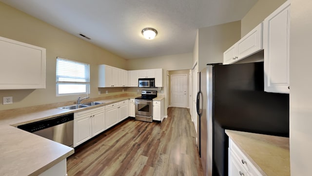 kitchen with white cabinetry, sink, stainless steel appliances, and dark hardwood / wood-style floors