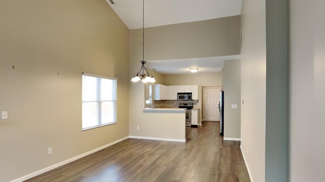 kitchen featuring white cabinetry, hanging light fixtures, high vaulted ceiling, hardwood / wood-style floors, and appliances with stainless steel finishes