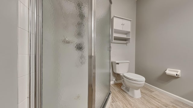 bathroom with toilet, an enclosed shower, and hardwood / wood-style flooring