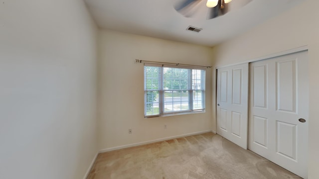 unfurnished bedroom featuring light carpet, a closet, and ceiling fan