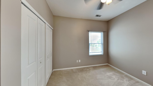 unfurnished bedroom with ceiling fan, light colored carpet, and a closet