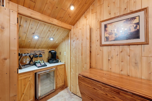 bar with light carpet, wooden ceiling, vaulted ceiling with beams, wine cooler, and wood walls