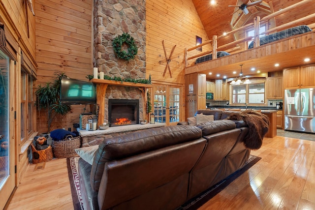 living room featuring a wealth of natural light, wooden walls, high vaulted ceiling, and light hardwood / wood-style floors