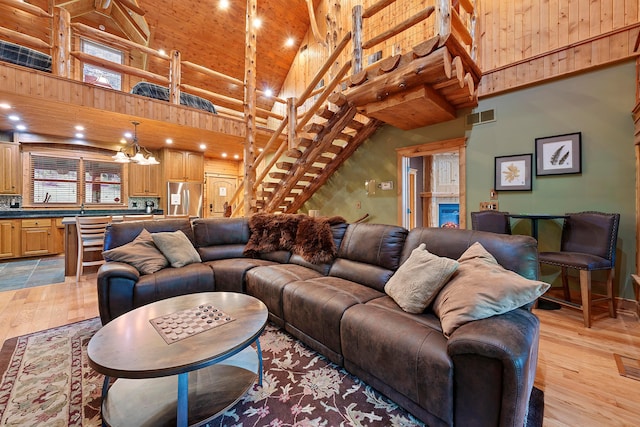 living room with high vaulted ceiling, light hardwood / wood-style floors, and an inviting chandelier