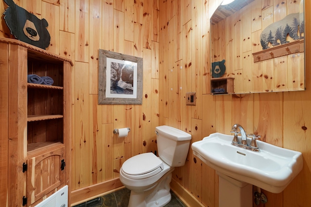 bathroom featuring sink, toilet, and wood walls