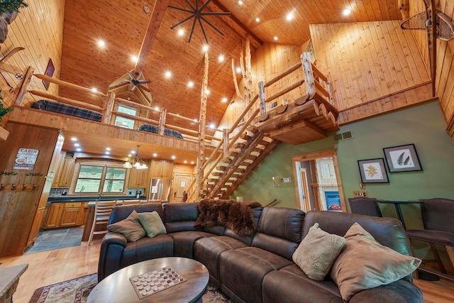 living room featuring beam ceiling, light hardwood / wood-style flooring, high vaulted ceiling, wood ceiling, and ceiling fan with notable chandelier