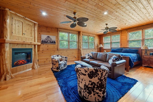 living room featuring wooden walls, ceiling fan, light hardwood / wood-style floors, and wooden ceiling