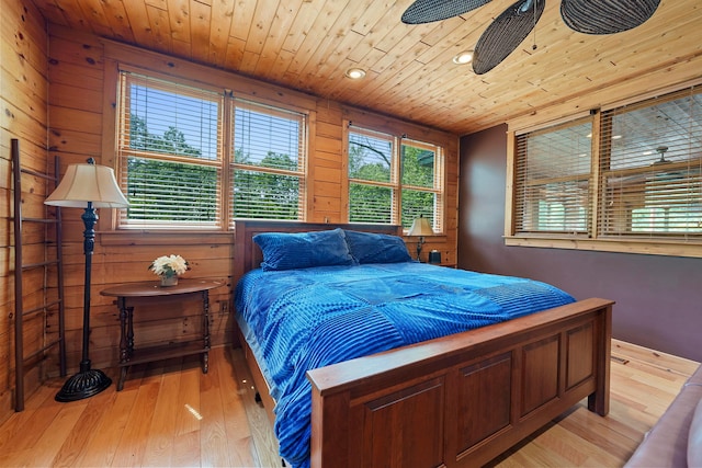 bedroom with ceiling fan, wooden ceiling, wood walls, and light wood-type flooring