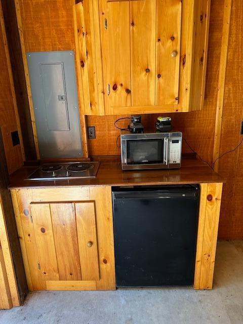 kitchen with stovetop, black fridge, and electric panel