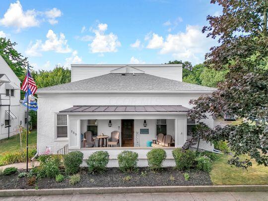 rear view of house with a porch and a yard