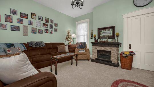 living room with light carpet, a fireplace, and an inviting chandelier