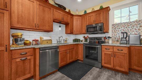 kitchen with decorative backsplash, light stone counters, sink, and appliances with stainless steel finishes