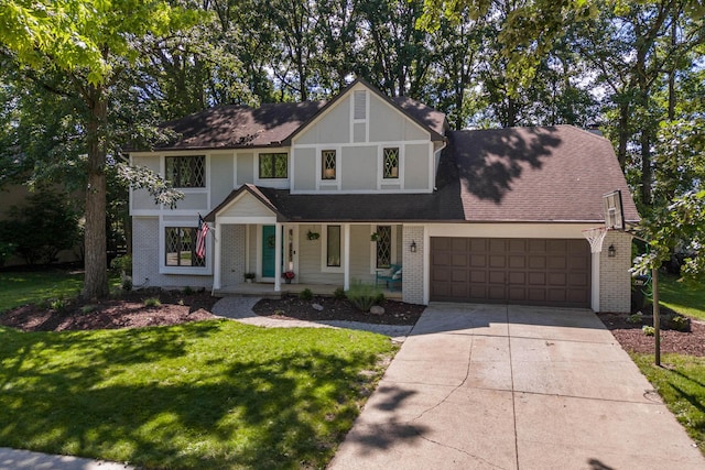 view of front of home featuring driveway, brick siding, an attached garage, covered porch, and a front yard