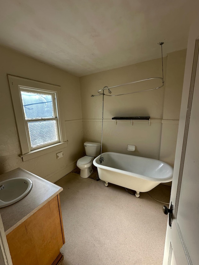 bathroom with a washtub, vanity, and toilet