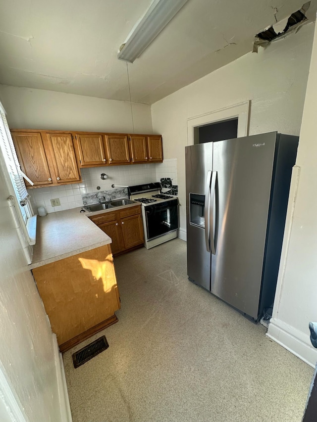 kitchen with tasteful backsplash, stainless steel refrigerator with ice dispenser, sink, and range with gas stovetop