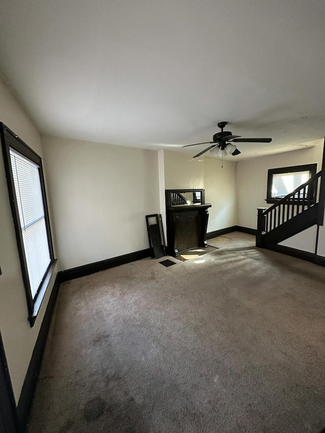 unfurnished living room with carpet floors, plenty of natural light, and ceiling fan