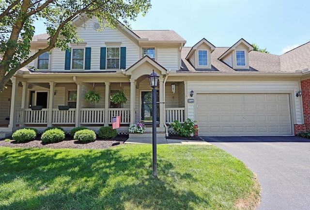 view of front of house with a front yard, a porch, and a garage