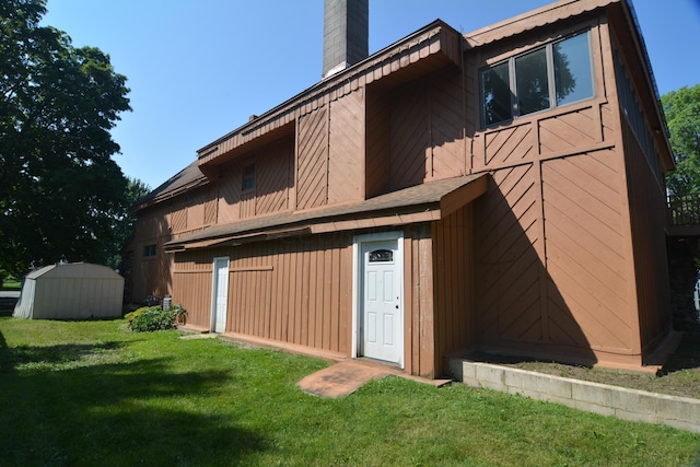 back of property with a shed and a yard