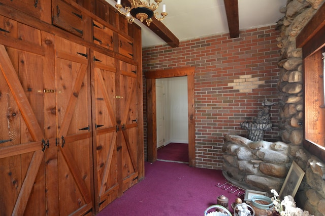 interior space with beamed ceiling, brick wall, and dark colored carpet