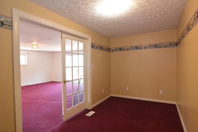 unfurnished room with carpet flooring, plenty of natural light, french doors, and a textured ceiling