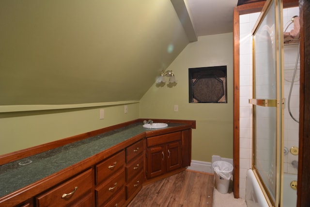 bathroom with hardwood / wood-style flooring, vanity, shower / bath combination with glass door, and lofted ceiling