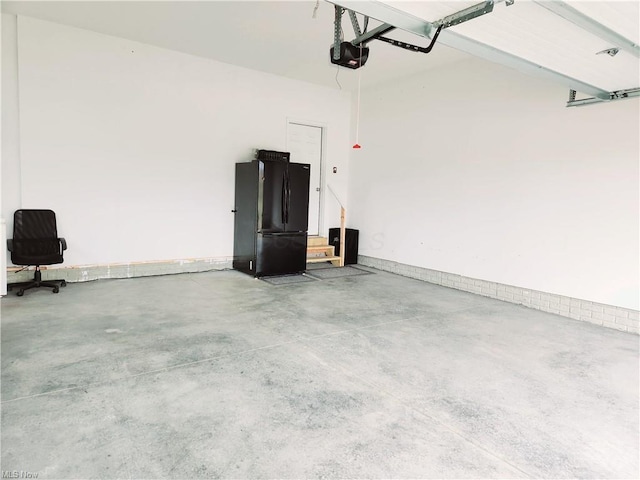 garage with a garage door opener and black refrigerator