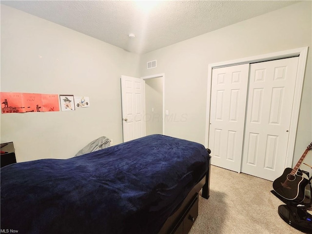 bedroom featuring a closet, light carpet, and a textured ceiling