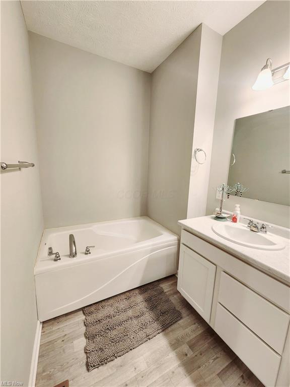 bathroom featuring vanity, a tub, hardwood / wood-style floors, and a textured ceiling