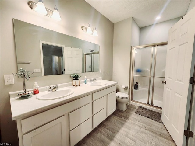 bathroom with hardwood / wood-style flooring, vanity, toilet, and a shower with shower door